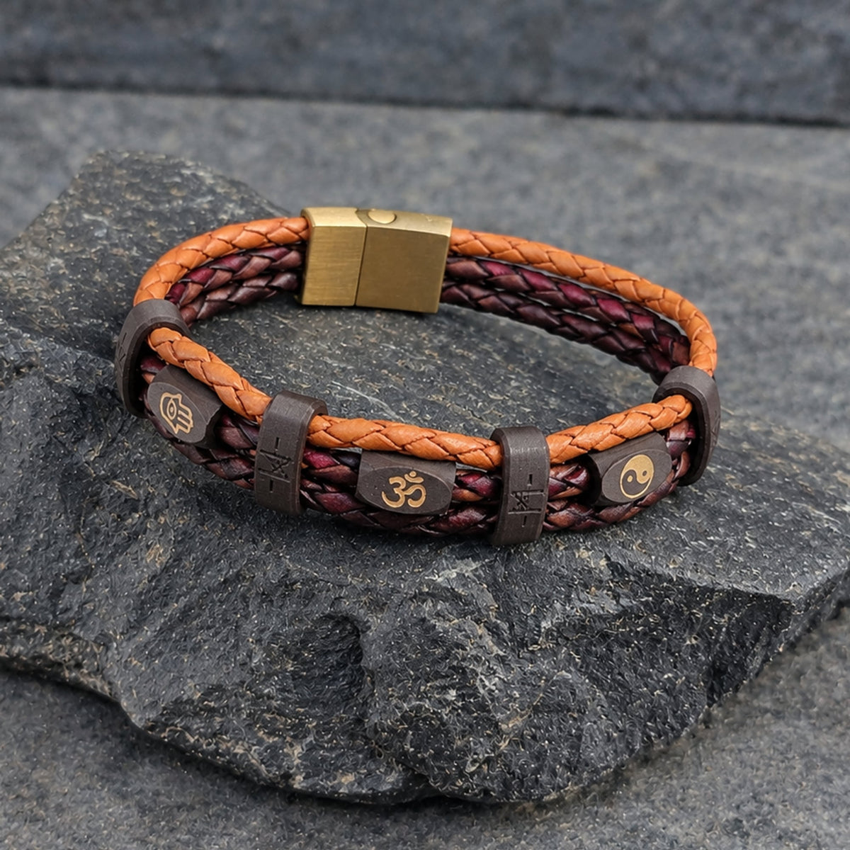 Mantra · Banded Leather in Tibet: tan leather outer braids · maroon centre braid · dark-brown beads · gold hamsa, om + yin yang · brown bands · brass slide-lock clasp